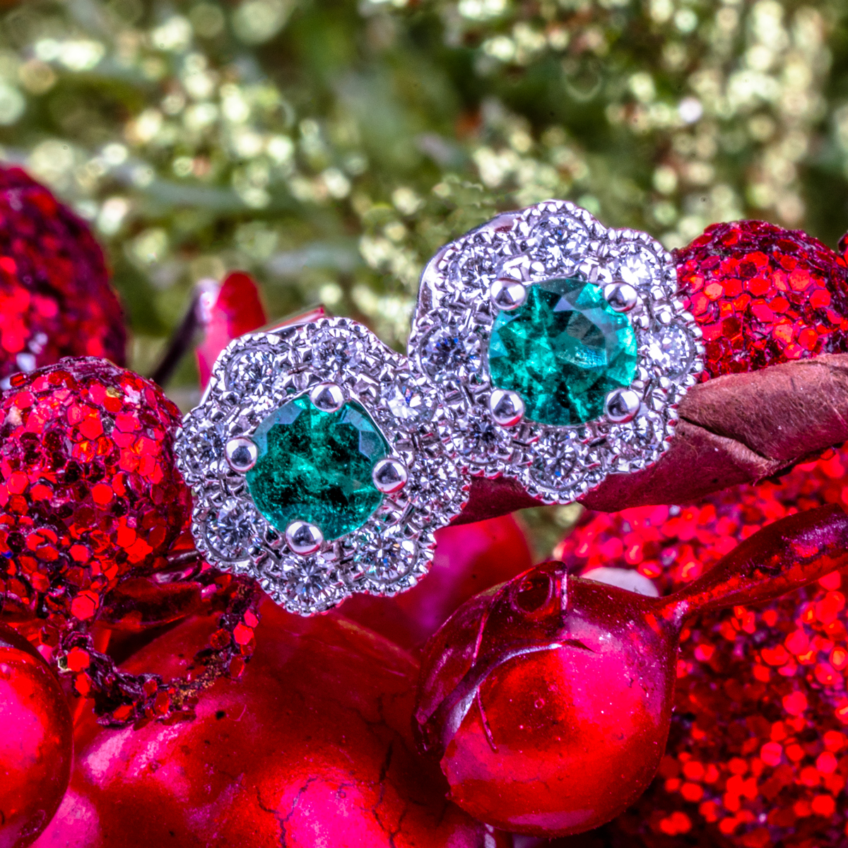 White gold floral stud earrings centered with round cut emeralds surrounded by diamond haloes.