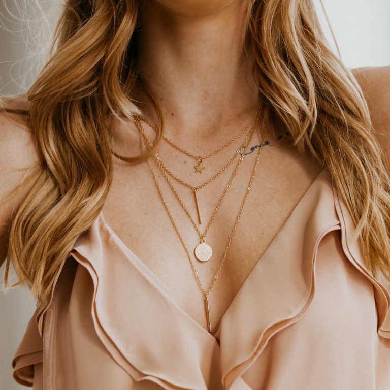 Up close shot of blonde woman wearing layered necklaces and a blouse